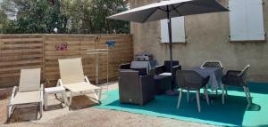 a patio with a table and chairs and an umbrella at Le Cocon des Vignes in Vidauban