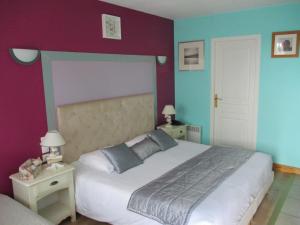 een slaapkamer met een groot bed met paarse en blauwe muren bij Les Augustines in Quend