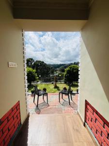 a room with two benches on a patio with a view at Green Hills Cottage in Aravankādu