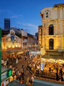 a group of people sitting at tables in a street at night at Straits Heritage Hostel in Singapore