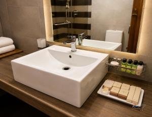 a bathroom with a white sink and a mirror at Rainbow Seven Hotel in Negombo