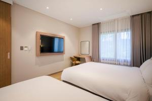 a hotel room with two beds and a flat screen tv at The Brighton Hamdeok in Jeju +41 photos