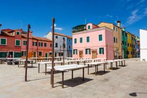 a group of benches in a street with colorful buildings at Casa Burano in Burano