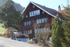 una casa de madera con un coche aparcado delante de ella en Bauernhaus Hinterbühle en Wolfhalden 