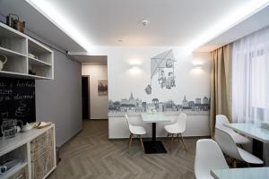 a dining room with a table and white chairs at Hotel Sacvoyage in Lviv