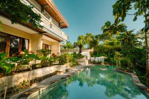 a swimming pool in front of a house at Arcana Ubud in Ubud