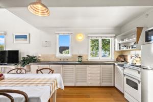 a kitchen with white cabinets and a table and chairs at The Stables - Charming Loft with Derwent River Views in Sandy Bay +22 photos