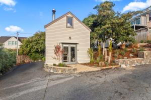 a small white house on the side of a street at The Stables - Charming Loft with Derwent River Views in Sandy Bay