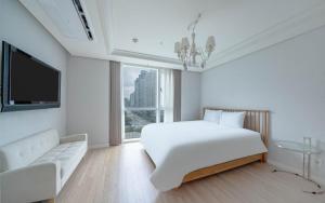 a white bedroom with a large bed and a couch at BS Centum hotel in Busan