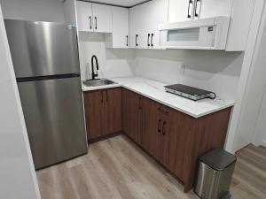 a kitchen with a stainless steel refrigerator and wooden cabinets at New Haven- 2-Bedroom Suite in Winnipeg +5 photos