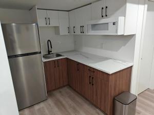a kitchen with a stainless steel refrigerator and wooden cabinets at New Haven- 2-Bedroom Suite in Winnipeg