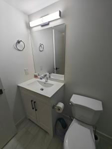 a bathroom with a toilet and a sink and a mirror at New Haven- 2-Bedroom Suite in Winnipeg