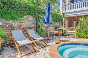 a pair of chairs and an umbrella next to a swimming pool at Hamilton Carriage A - Amazing Location, Courtyard in Savannah