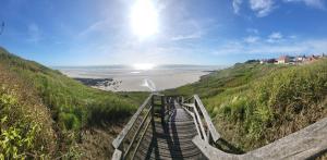 a boardwalk leading to a beach on a hill at Les Oyats in Équihen-Plage