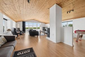 an open living room with a wooden ceiling at Spacious Holiday Home With Water View in Redsted