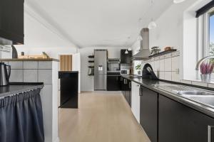 a large kitchen with black and white appliances at Spacious Holiday Home With Water View in Redsted +18 photos