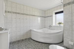 a white bathroom with a tub and a window at Spacious Holiday Home With Water View in Redsted