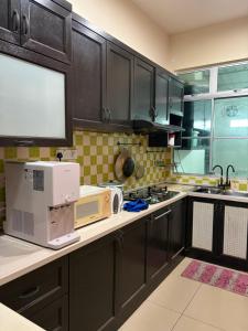 a kitchen with black cabinets and white appliances at D Aida Homestay Bukit Katil in Kampong Bukit Katil