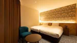 a hotel room with a bed and a blue chair at ホテルドゥアッシュ in Kushiro