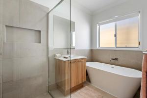 a bathroom with a tub and a sink and a window at Kinma Valley Retreat KVR in Morayfield +12 photos