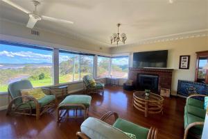 a living room with chairs and a fireplace and windows at 13 High Street in Nambucca Heads
