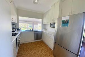a kitchen with a stainless steel refrigerator and white cabinets at 13 High Street in Nambucca Heads +15 photos