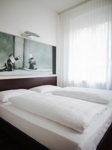 2 camas blancas en un dormitorio con ventana en arte Hotel Linz en Linz