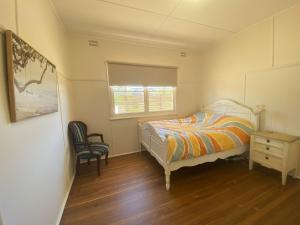 a bedroom with a bed and a chair and a window at 10 Clarke in Nambucca