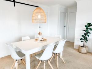 a white dining room with a white table and white chairs at 59 Short in Nambucca Heads