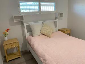 a bedroom with a bed with pink sheets and a window at Charming Beach Getaway in Valla Beach