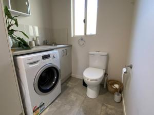 a bathroom with a toilet and a washing machine at Charming Beach Getaway in Valla Beach +20 photos