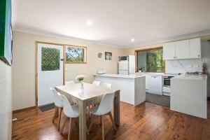 a kitchen with a wooden table and white cabinets at Coastal Charm in Valla Beach