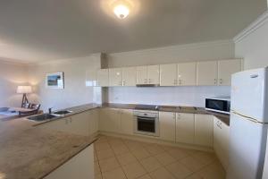 a kitchen with white cabinets and a sink and a refrigerator at Estuary in Nambucca Heads