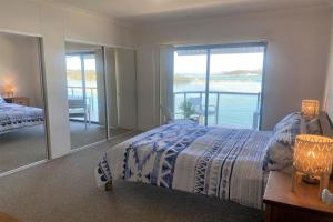 a bedroom with a bed and a view of the water at Estuary in Nambucca Heads