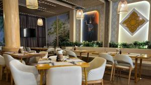 a restaurant with wooden tables and white chairs at CLOVER HOTEL MONIVONG By LEE in Phnom Penh