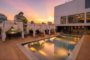 a swimming pool with chairs and a building at CLOVER HOTEL MONIVONG By LEE in Phnom Penh
