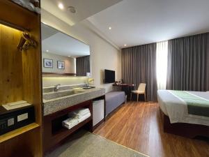 a hotel room with a bed and a sink and a mirror at CLOVER HOTEL MONIVONG By LEE in Phnom Penh
