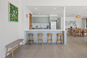 a kitchen and living room with a counter and stools at Coastal Chill in Nambucca Heads +19 photos