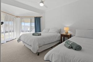 a white bedroom with two beds and a window at Coastal Chill in Nambucca Heads