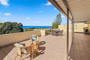 a patio with wicker chairs and a table on a balcony at Coastal Chill in Nambucca Heads
