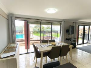 a dining room with a table and chairs and a balcony at Karingal in Nambucca Heads