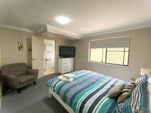 a bedroom with a bed and a chair and a television at Karingal in Nambucca Heads