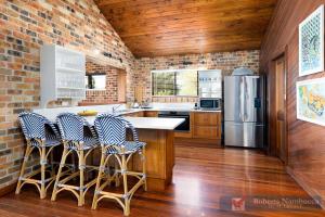 a kitchen with a brick wall and a kitchen island with bar stools at 57Charlton in Nambucca Heads