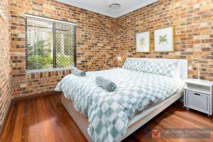 a bedroom with a bed and a brick wall at 57Charlton in Nambucca Heads