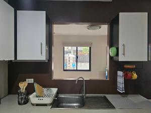 a kitchen with white cabinets and a sink and a window at Kasa Boutique Residence in Cebu City