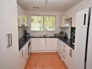 a kitchen with white cabinets and black counter tops at Riverwood in Nambucca Heads