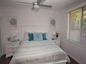 a white bedroom with a bed and a ceiling fan at Riverwood in Nambucca Heads
