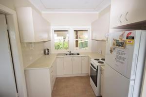 a kitchen with white cabinets and a white refrigerator at The Outlook in Nambucca Heads +8 photos