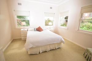a white bedroom with a bed and two windows at The Outlook in Nambucca Heads