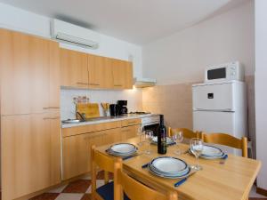 a kitchen with a wooden table with plates and wine glasses at Apartments AVA in Poreč